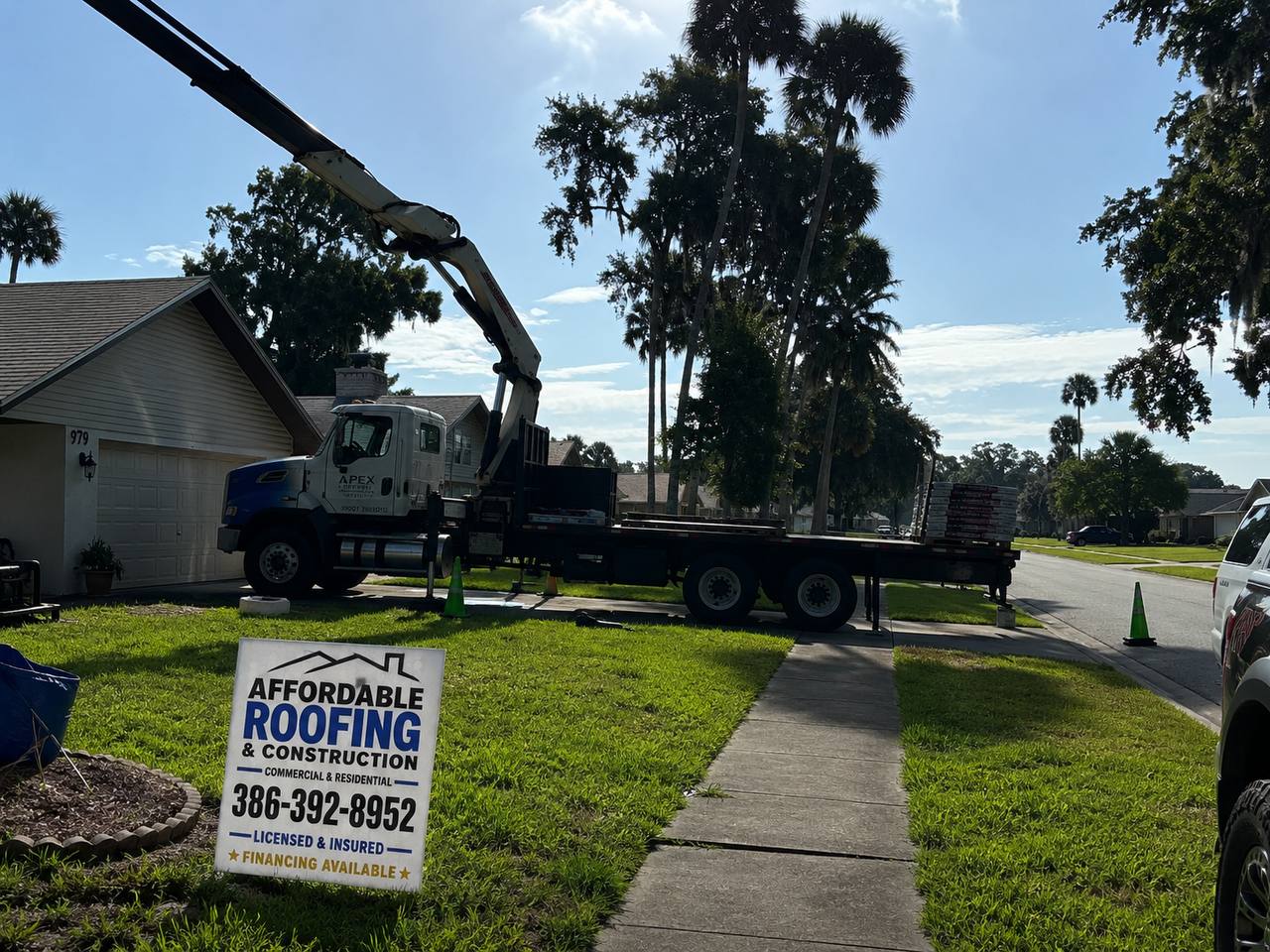 Affordable Roofing and Construction yard sign at residential job site in Volusia County Florida with delivery truck unloading roofing materials