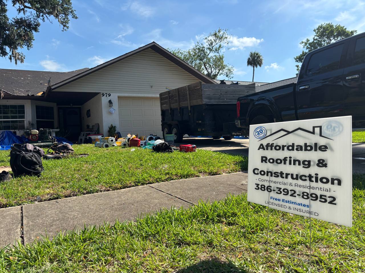 Roofing contractor yard sign with truck and trailer in driveway — Port Orange FL roof replacement job site